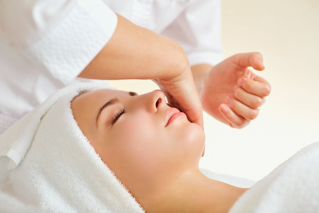 A person receiving a Japanese Kobido face lift massage, lying down with a towel on the head.